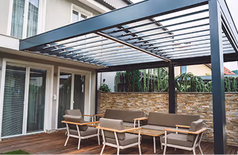 Moderner Außenbereich mit Pergola über Holzterrasse und Sitzbereich mit Stühlen und Sofa.