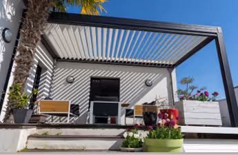 Moderner Außenbereich mit Pergola, Terrassenmöbeln, Pflanzen und klarem blauem Himmel.